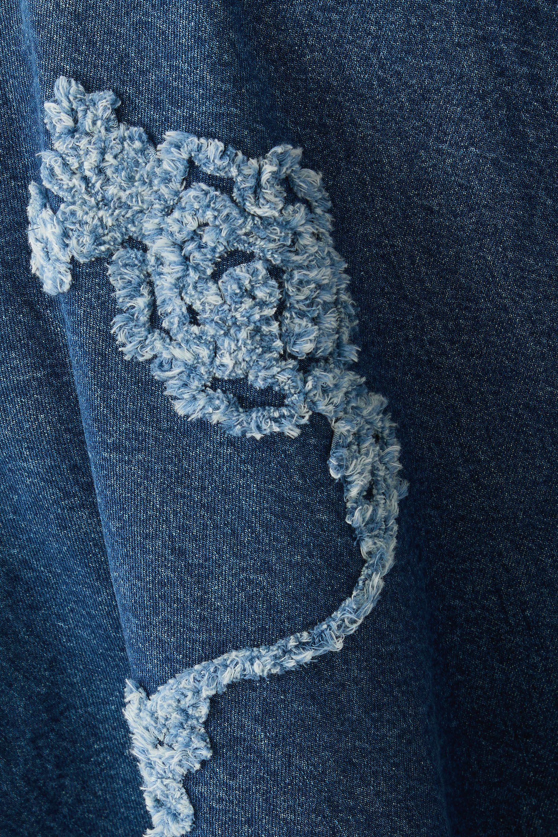 تنورة متوسطة الطول بتطريزات زهور دنيم